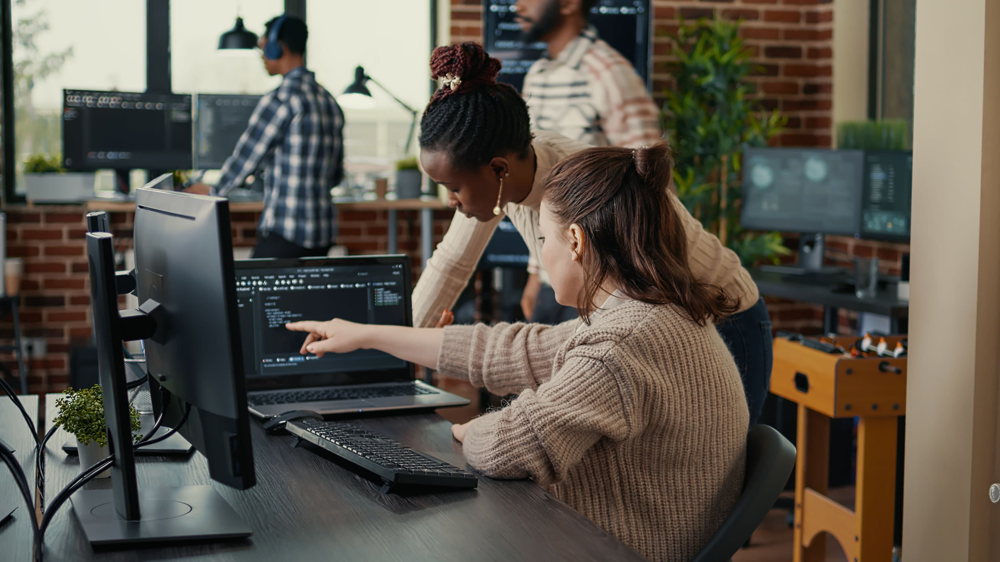 Ein Team von Softwareentwicklern arbeitet kollaborativ an einem Code auf Computern in einem Büro mit modernem, industriellem Design.